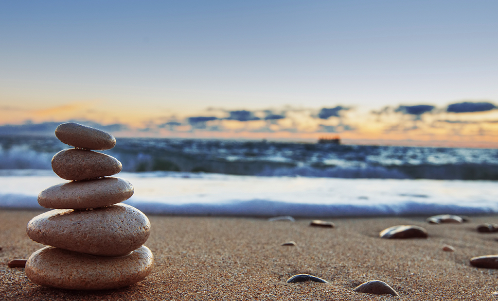 A stack of rocks on the beach near water